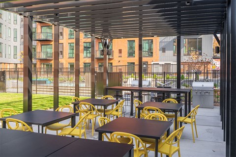 A patio with tables and chairs and a building in the background.