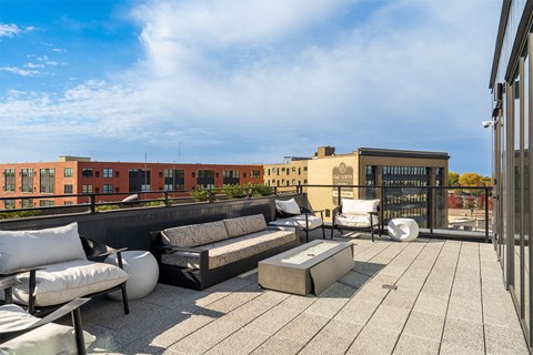 A rooftop patio with white furniture and a black railing.