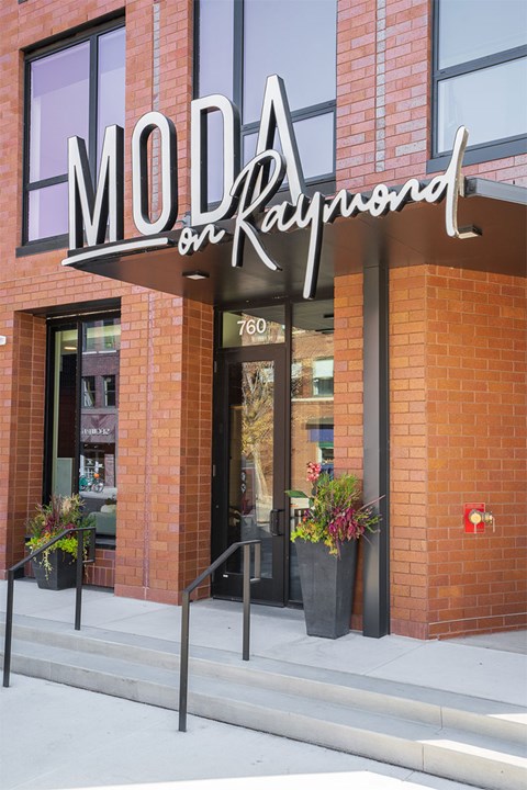 A brick building with a sign that says Moda on Raymond.