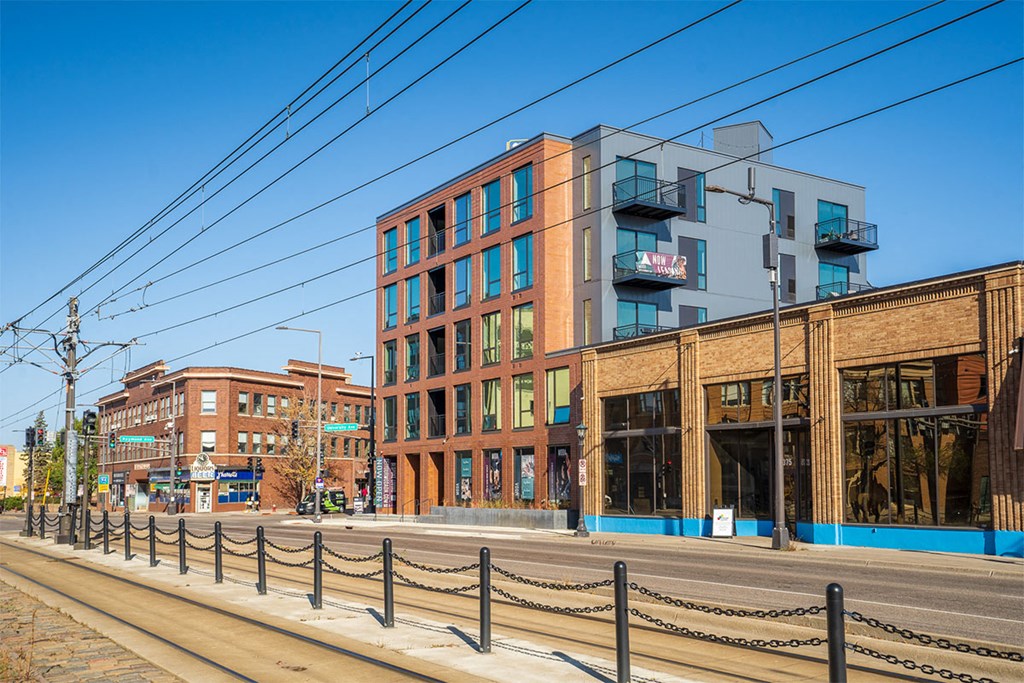 A street view of a city with buildings and a fence.