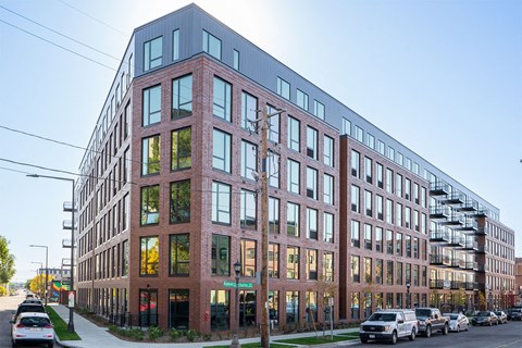 A modern red brick building with a glass facade and a metal staircase on the side.