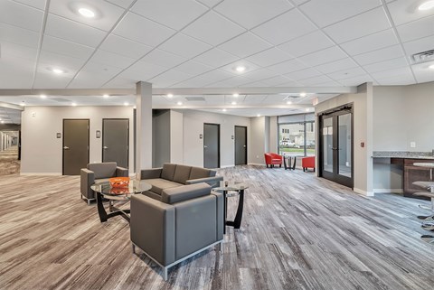 A spacious office lounge with grey couches and wooden flooring.