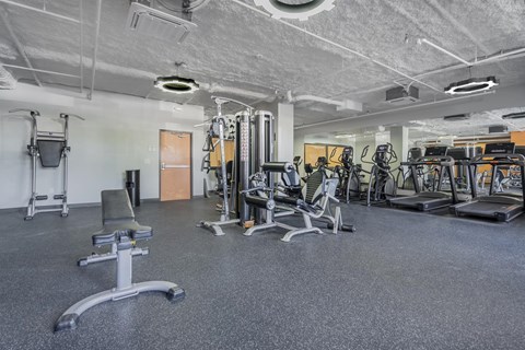 A gym with a variety of equipment including treadmills, weights, and exercise machines.