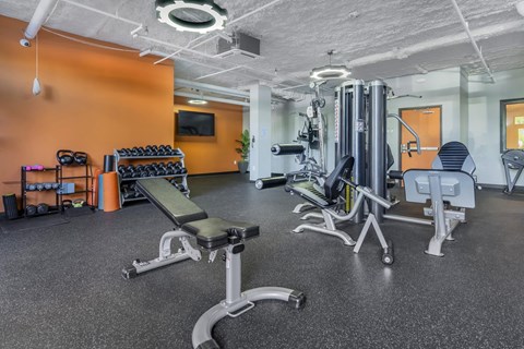 A gym with orange walls and a variety of equipment.