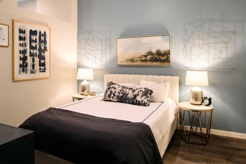 A bedroom with a large bed and two lamps.