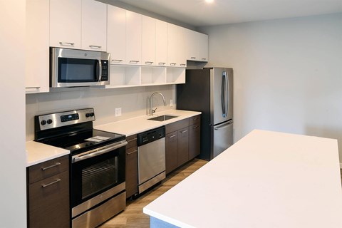 A kitchen with a white counter top and stainless steel appliances.