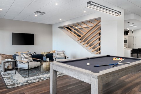 A pool table is in the middle of a room with a TV and a couch.