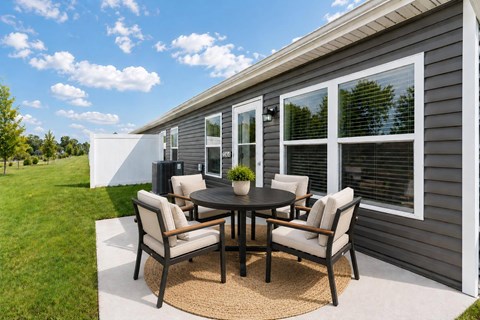 A patio with a table and chairs is set up outside a house.