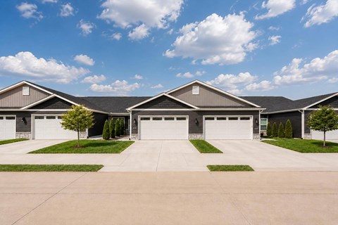 A large, modern house with a grey roof and white garage doors.