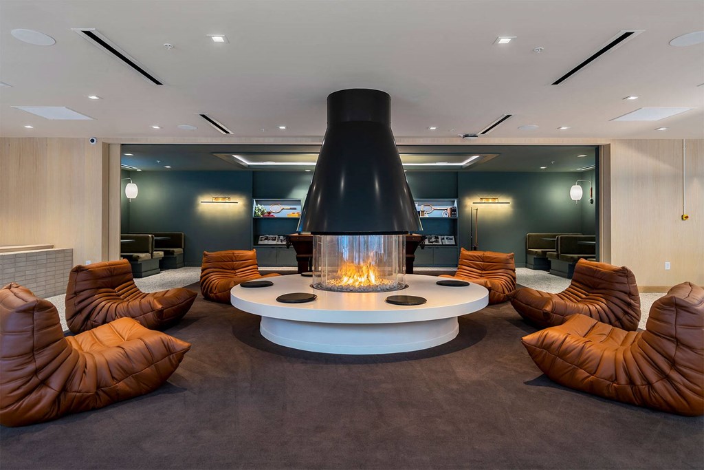 A modern living room with a fireplace and brown leather chairs.