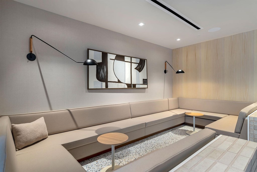 A modern living room with a grey sofa, a wooden coffee table, and a large mirror on the wall.