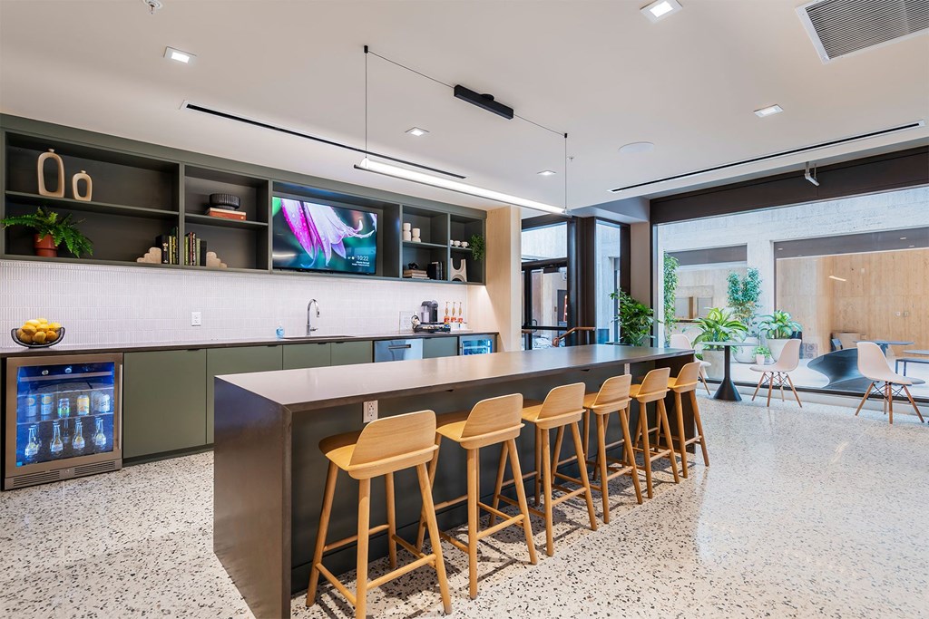 A modern kitchen with a bar area and wooden stools.