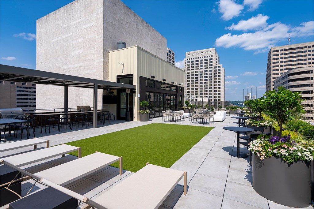 A modern outdoor seating area with a green lawn and a large planter.