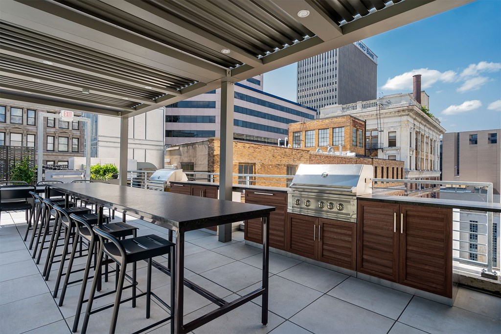 A rooftop patio with a long table and chairs.