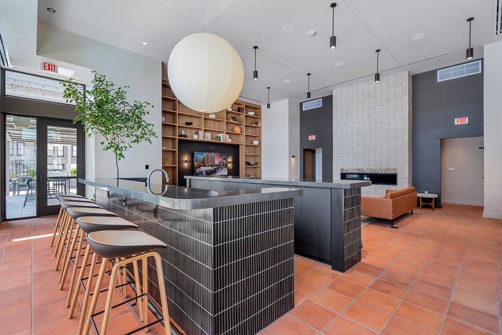 A modern bar with a black and white tiled counter and wooden stools.