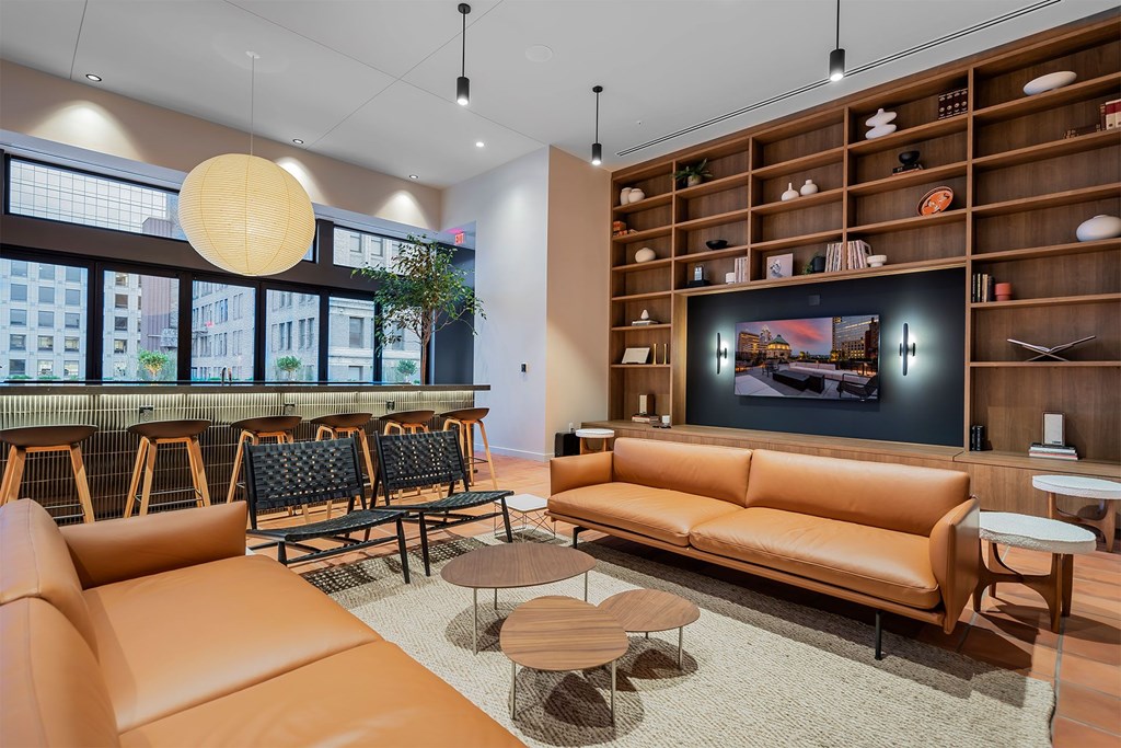 A modern living room with a large orange sofa and a wooden shelf with various objects on it.