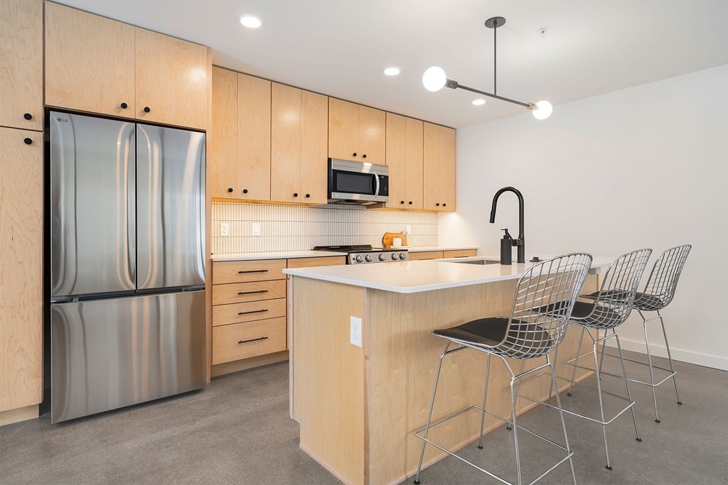 A kitchen with wooden cabinets and a stainless steel refrigerator.