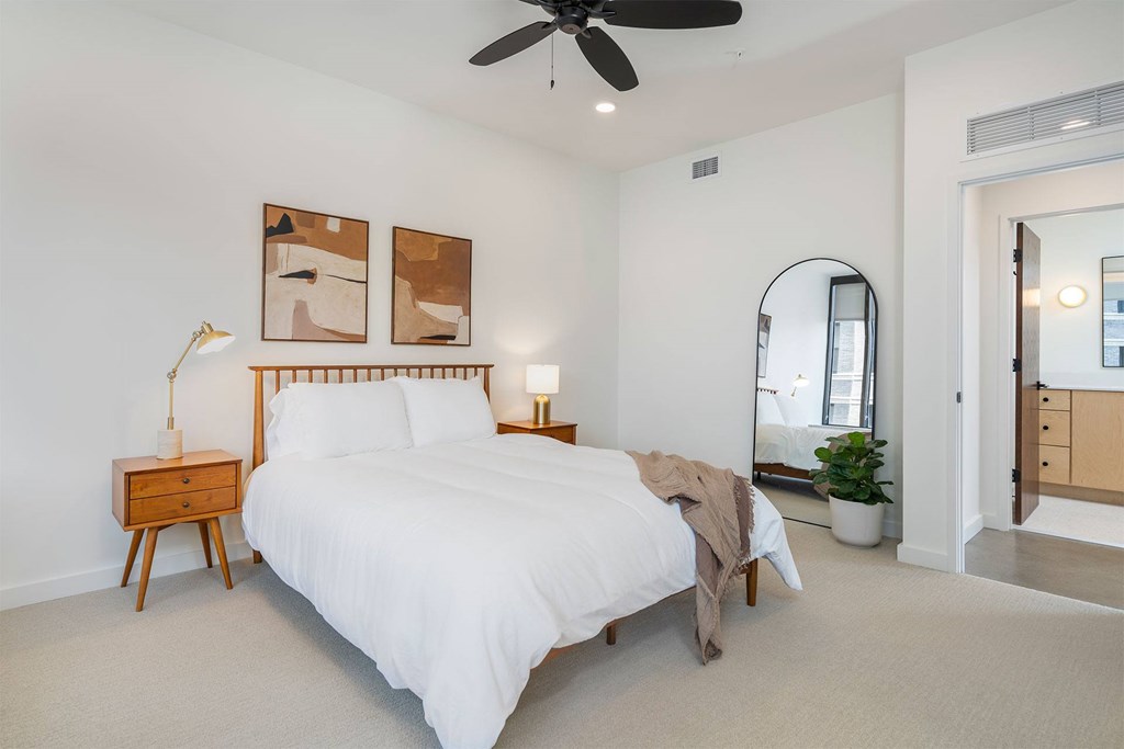 A bedroom with a large bed and a ceiling fan.
