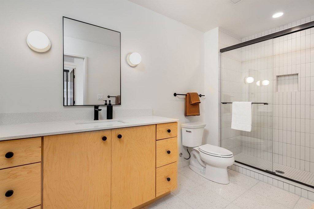 A bathroom with a toilet, sink, and mirror.