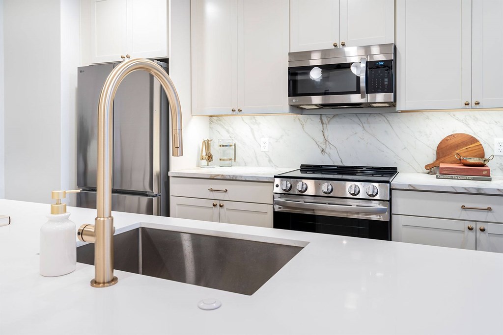 A modern kitchen with a stainless steel refrigerator, a sink, and a stove.