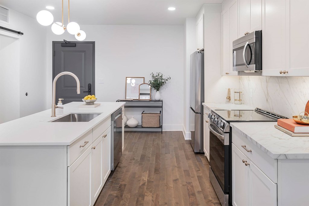 A modern kitchen with white cabinets and a wooden floor.