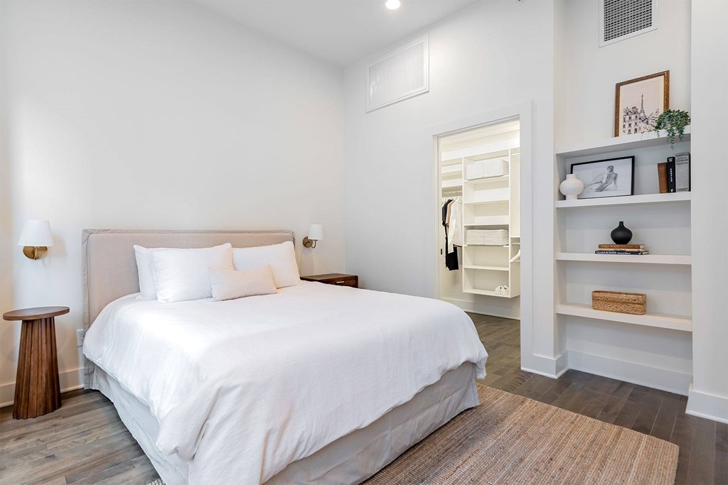 A white bedroom with a large bed and a wooden floor.