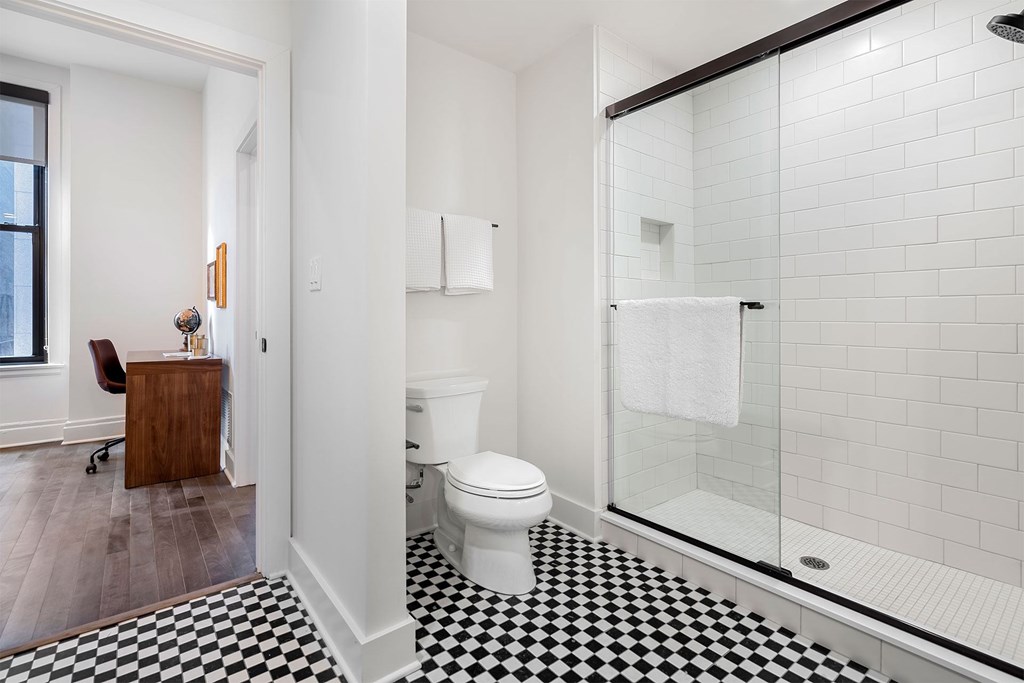 A white toilet in a bathroom with a black and white checkered floor.