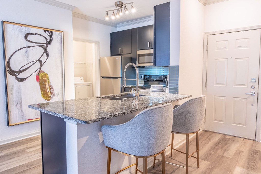 a kitchen with a marble counter top with three chairs