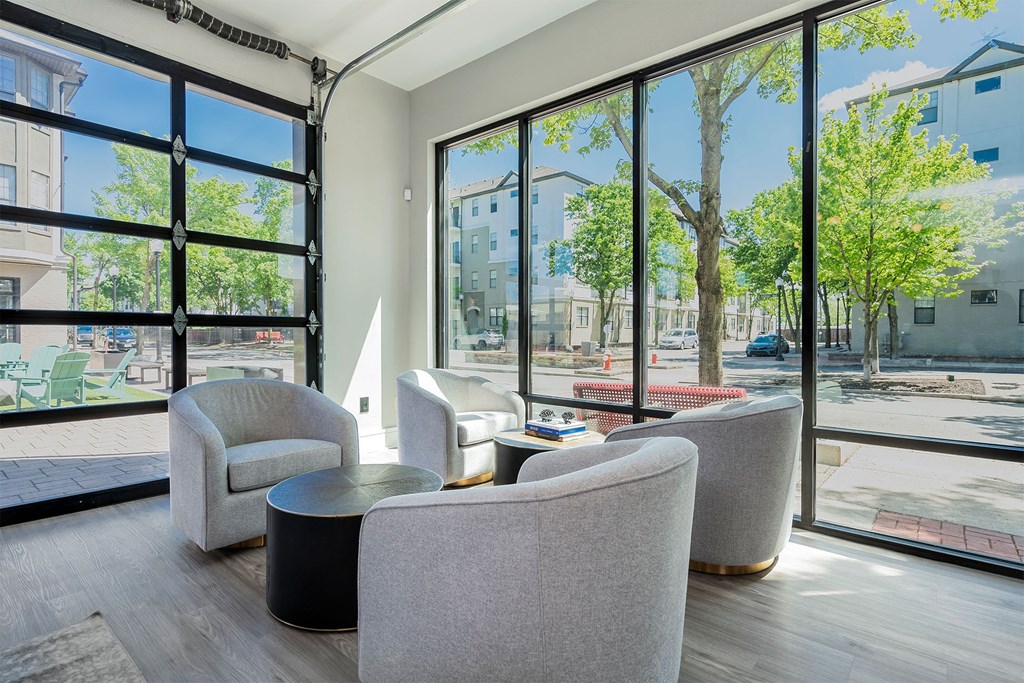 a lounge area with chairs and tables and large windows