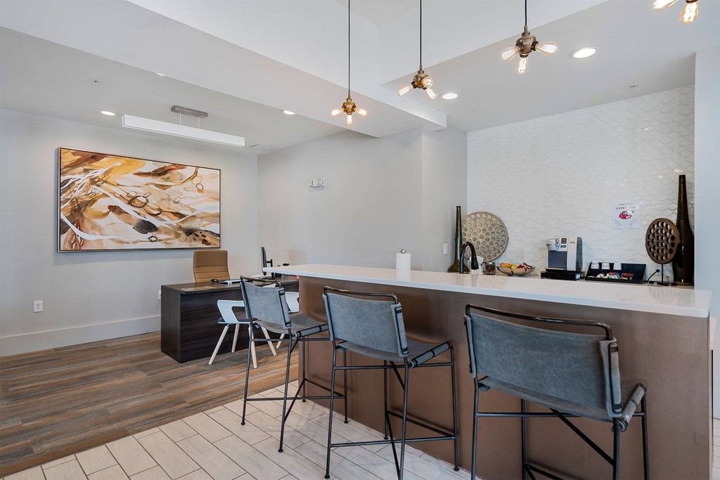 a bar with four stools in front of a counter with chairs