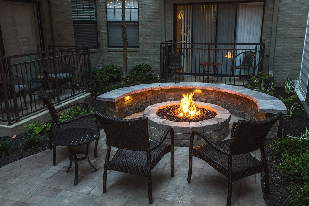 an outdoor patio with a fire pit and chairs