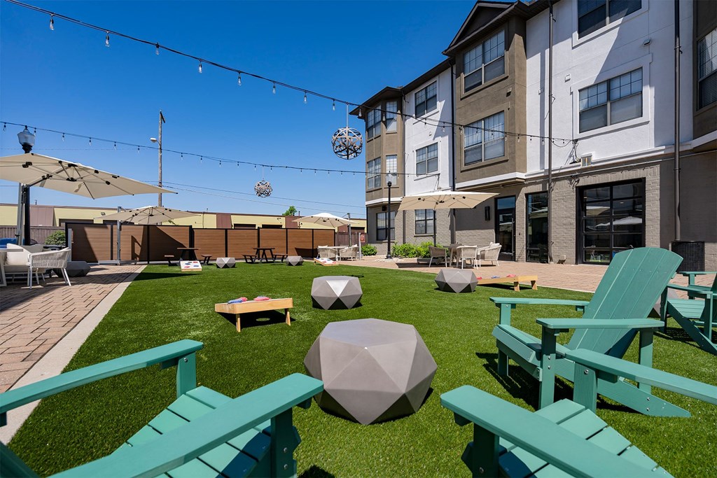 a backyard with green grass and chairs and a patio with umbrellas