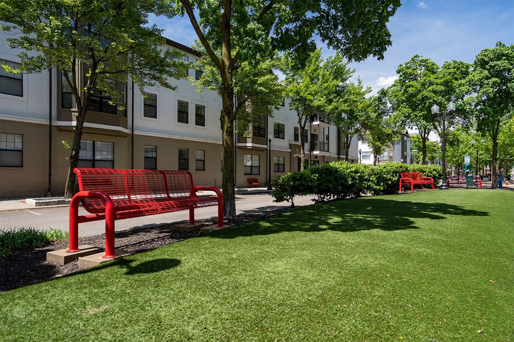 a park with benches and trees in front of an apartment building