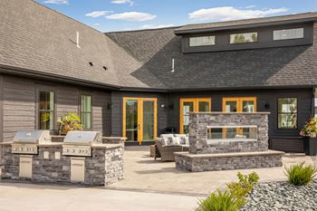a backyard patio with a grill and a stone fireplace