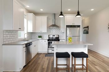 a kitchen with white cabinets and a large island with two stools