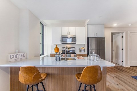 A modern kitchen with a white countertop and two yellow chairs.
