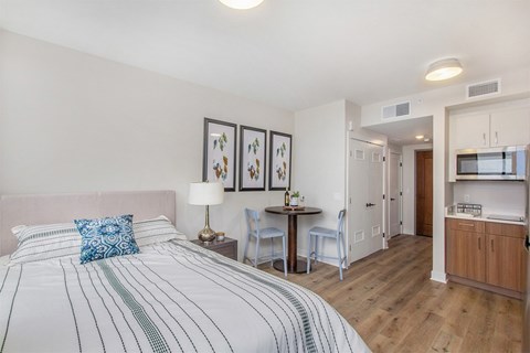 A bedroom with a large bed and a small kitchenette.