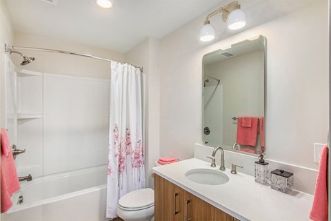 A white bathroom with a pink towel and a white shower curtain.