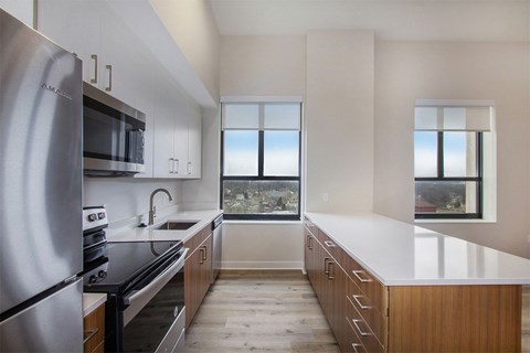 A kitchen with a stainless steel refrigerator and a window overlooking a cityscape.