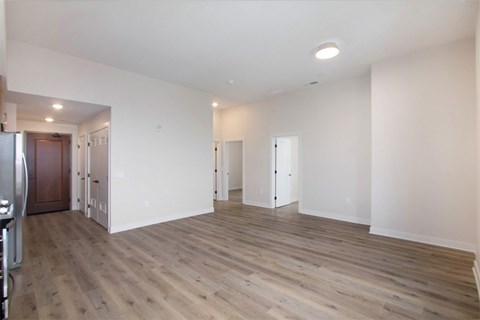 A spacious room with wooden flooring and white walls.