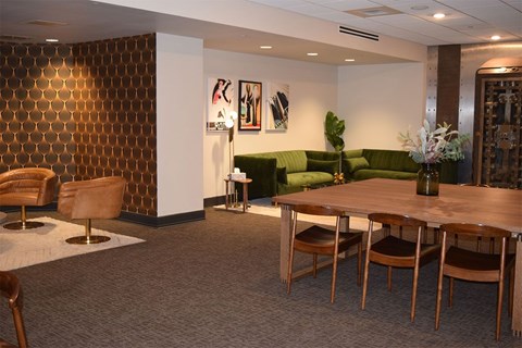A room with a brown and gold patterned wall and a green couch.