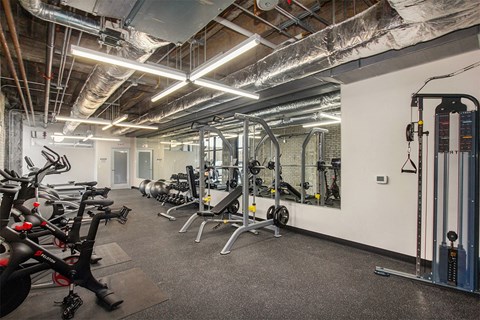 A gym with a variety of equipment including treadmills, weights, and exercise machines.