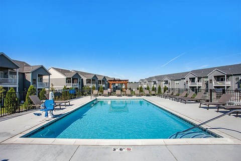 A large swimming pool surrounded by a fence and chairs.