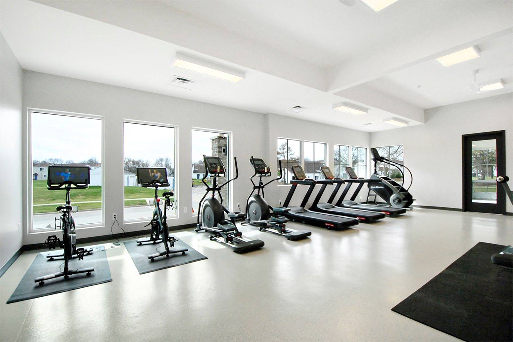 a gym with cardio equipment on the floor and windows