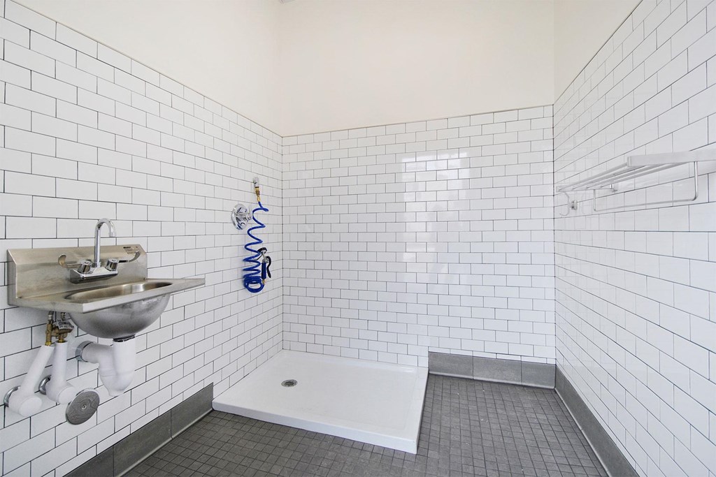 a white tiled bathroom with a sink and a shower