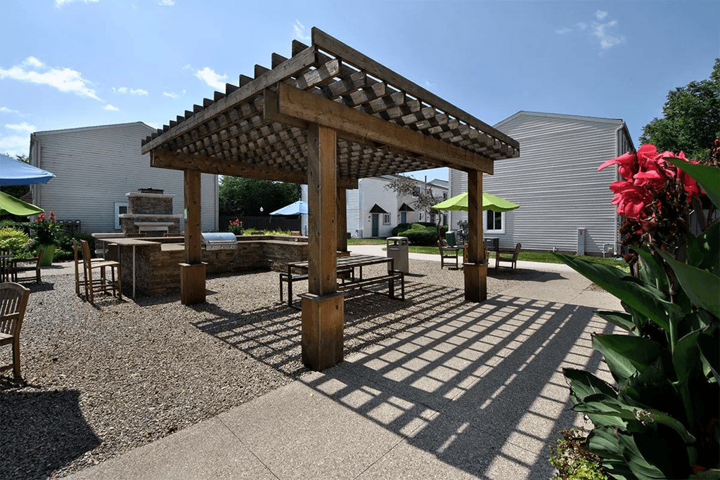 a pergola with tables and chairs in a courtyard
