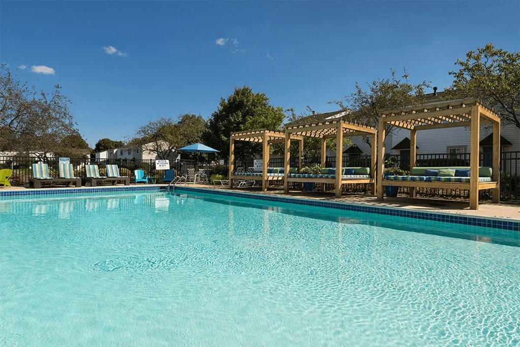 a large swimming pool with chairs and a pavilion