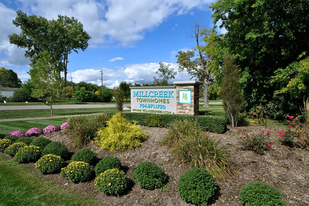 a sign townhomes in front of a flower garden