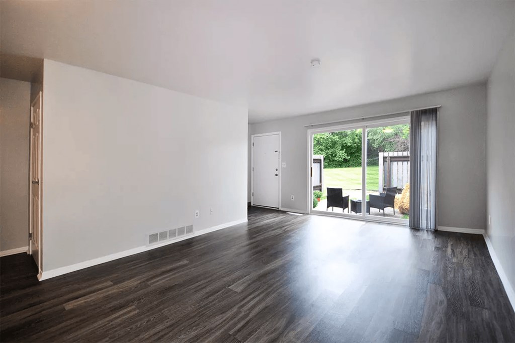 an empty living room with wood floors and a sliding glass door