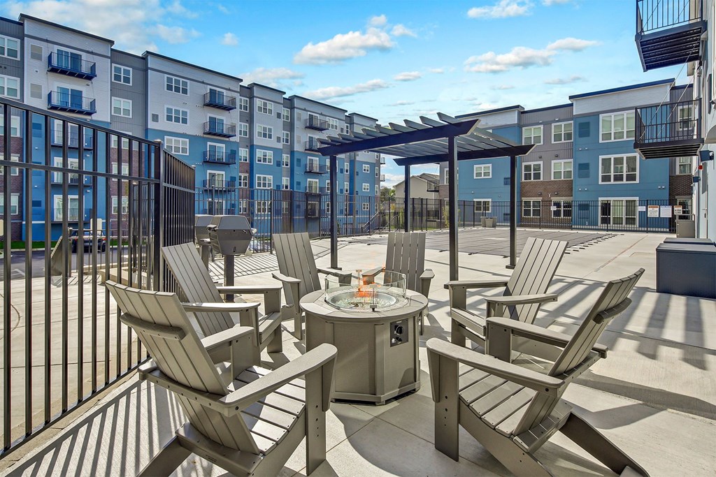an outdoor patio with chairs and a fire pit and an apartment building